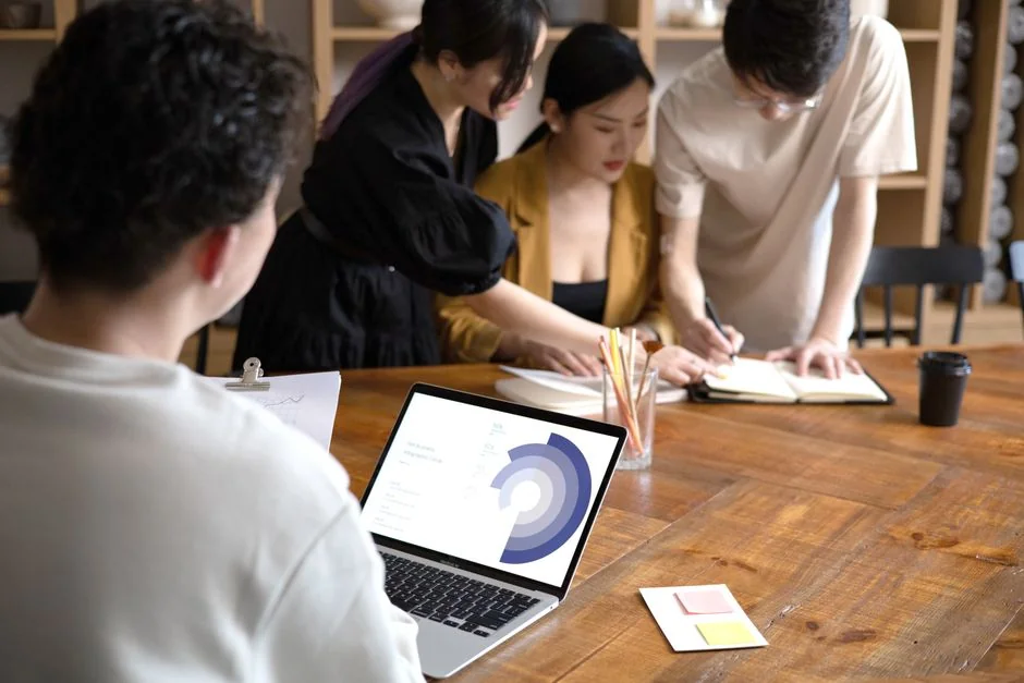 A modern workspace showing hands analyzing marketing data on a laptop and paper documents.